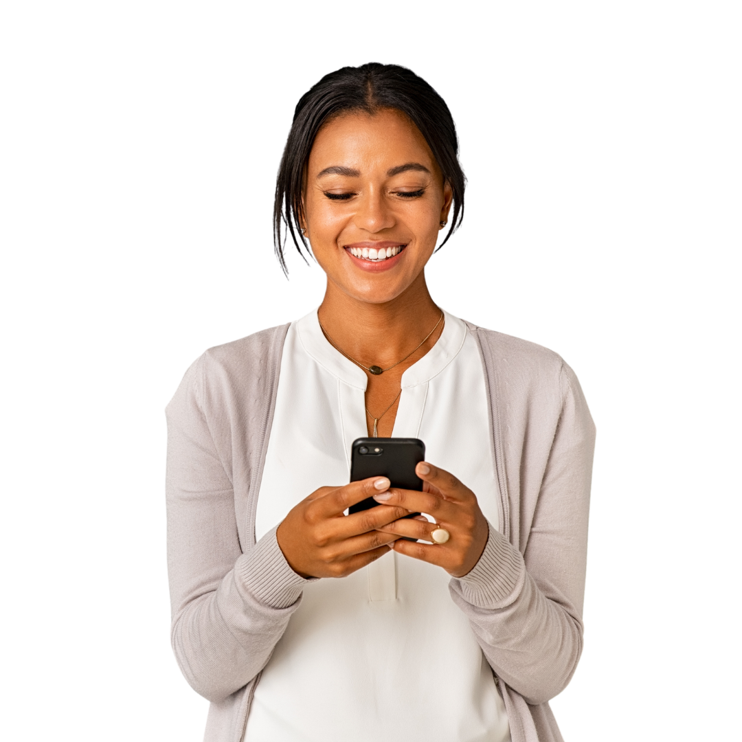 A smiling woman with dark brown hair wearing a light grey sweater and white blouse, looking down at a smartphone she's holding in her hands against a white background.