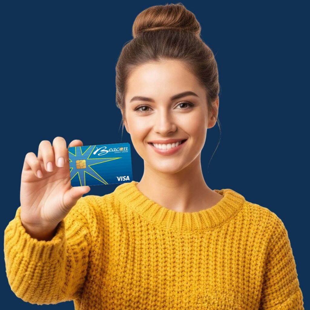 A smiling woman in a yellow knit sweater holding a yellow credit card against a blue background.
