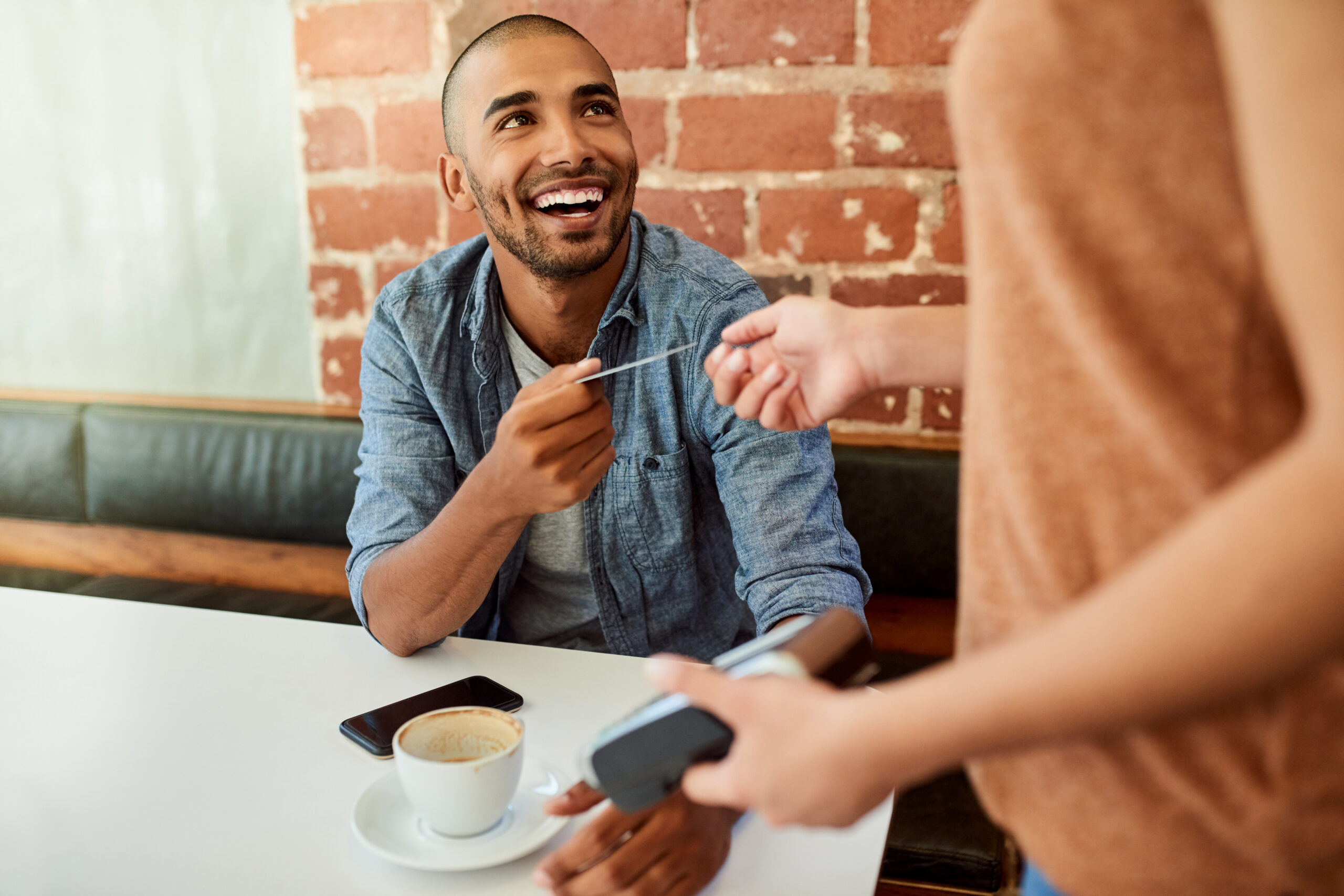 Shot of an unrecognizable barista accepting a credit card payment from a customer at a cafe