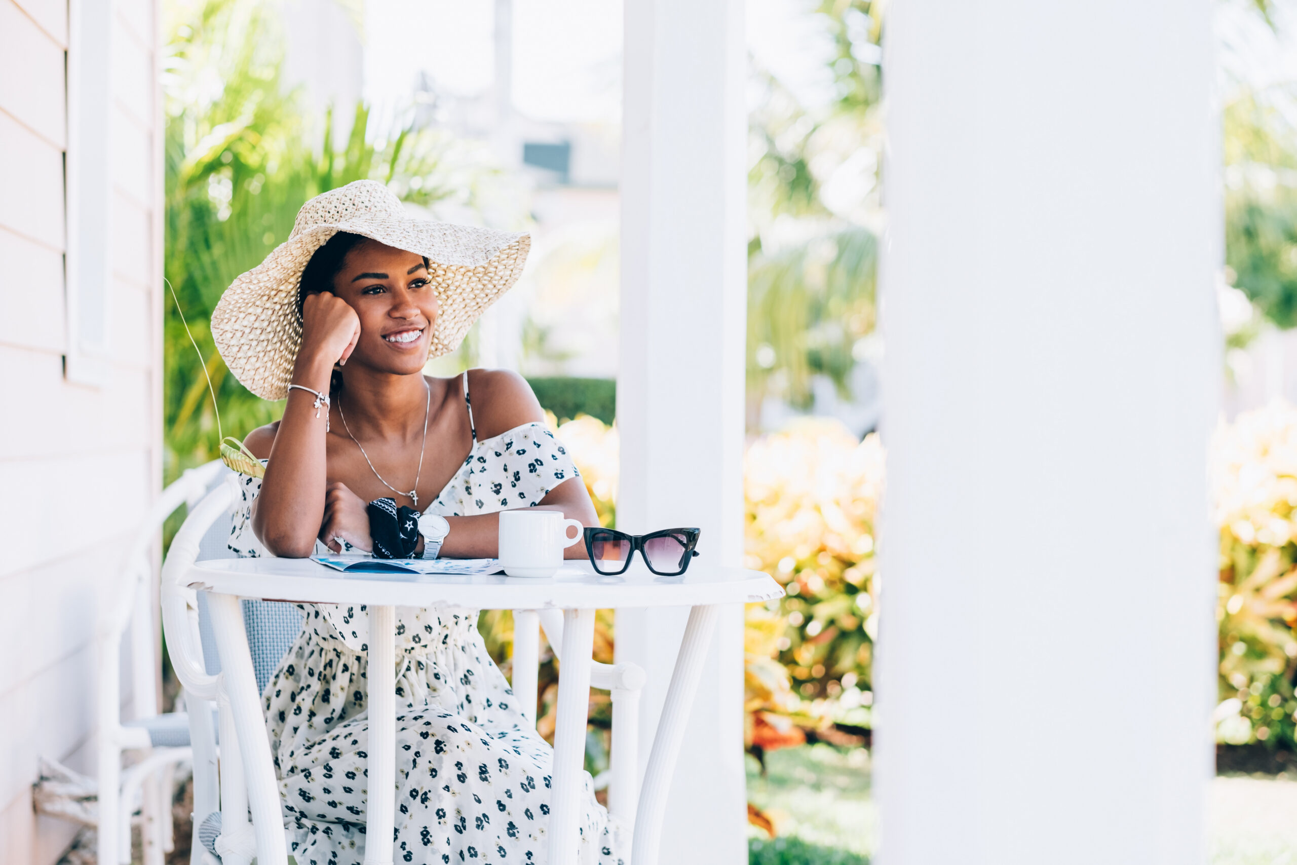 Millennial Black woman sitting at the patio table at summer resort. She is at the begging of her summer vacation in Caribbean.