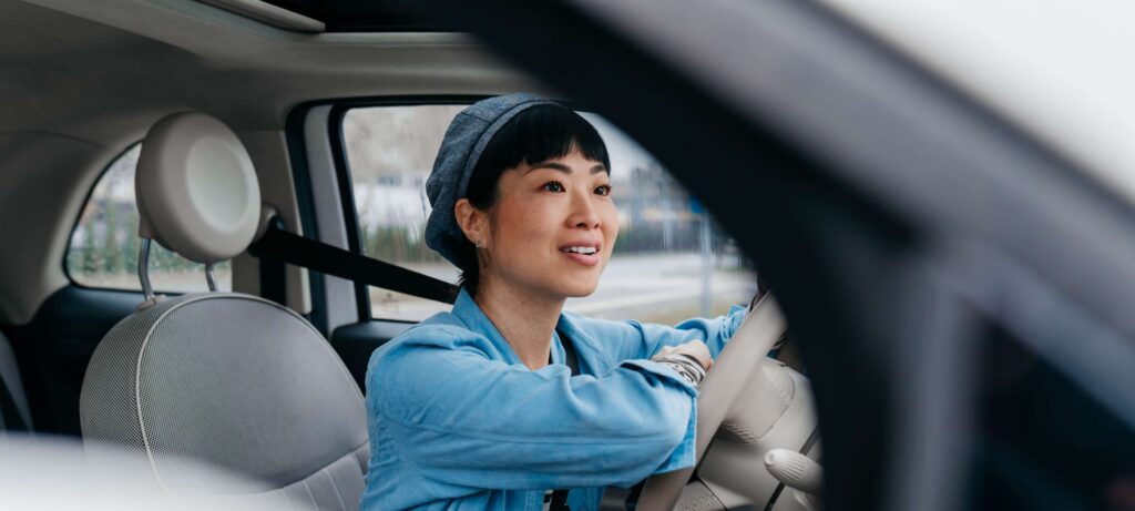 Auto refinance loan asian woman wearing blue jean top driving in car