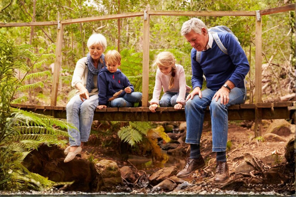 Grandparents with children sitting on a bridge.